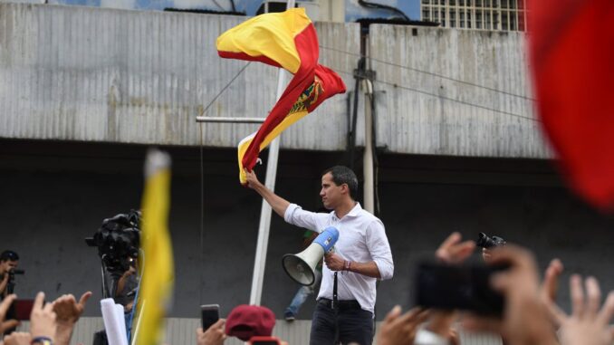 Venezuelan opposition leader Juan Guaidó, recognized by many in the international community as the legitimate interim ruler, waves a flag at a rally in Plaza Bicentenario, in Maracay, on April 26. (Carlos Becerra/Getty Images)