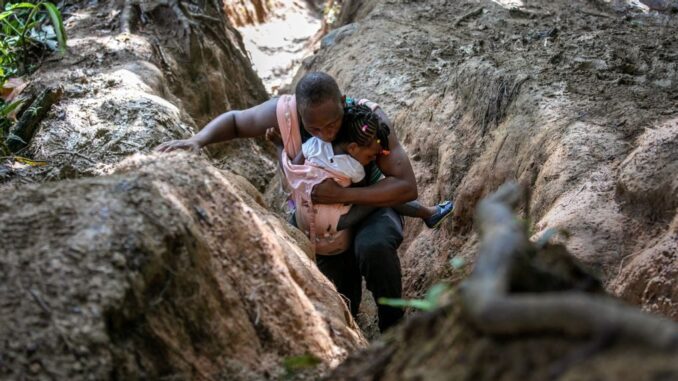 A Haitian father carries his daughter in the Darien Gap, between Colombia and Panama, on Oct. 5. It is the most dangerous passage for migrants walking through the Americas. They often hope to reach the United States, while others stay in Mexico. (John Moore/Getty Images)